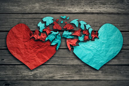 Romantic relationship concept as two hearts made of torn crumpled paper on weathered wood as symbol for romance attachment and exchange of feelings and emotions of love.